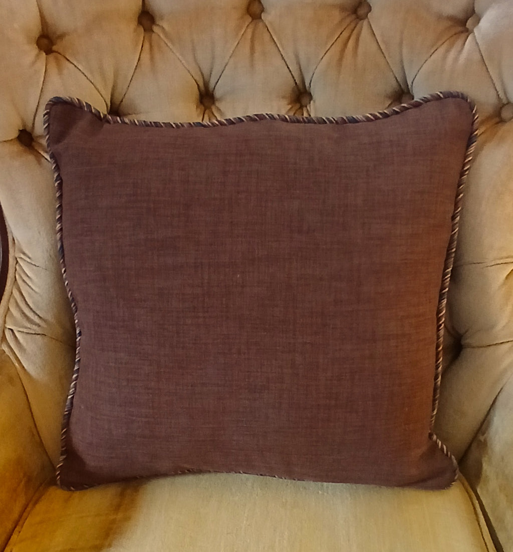 Handmade 18x18 cinnamon brown cotton throw pillow cover with multicolor twisted cord trim, styled on a tufted cream chair